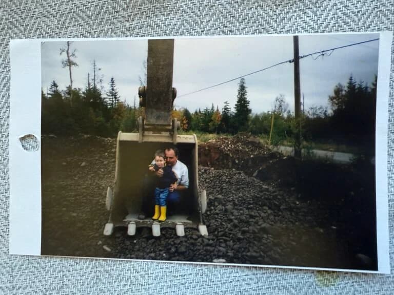 Father and child in excavator bucket — early inspiration for U-Dig It Rentals