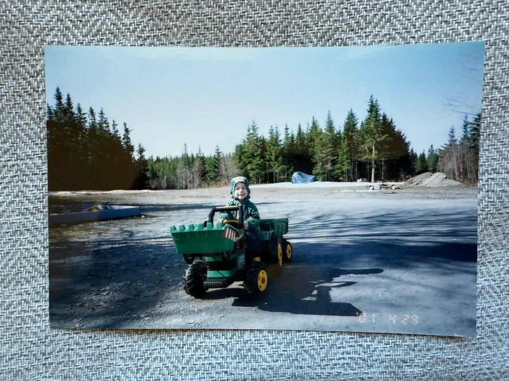 Young child driving a green toy dump truck — early roots of U-Dig It Rentals.